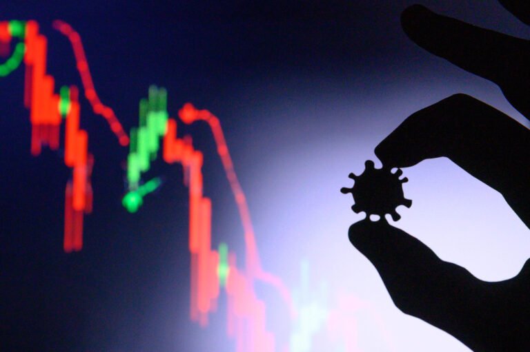 v pozadi grafy akcioveho trhu a ruku drzici virus jako symbol nove varianty covidu omikron
