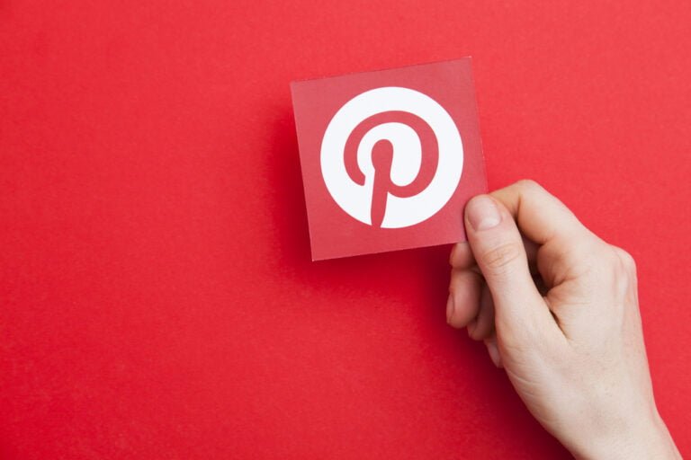 Ruka držící logo Pinterest. Pinterest je oblíbená sociální platfoma pro sdílení obrázků.