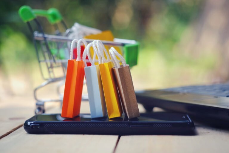 nákupní tašky na smartphonu, nákupní košík pozadí, koncept e-commerce a on-line nákupu