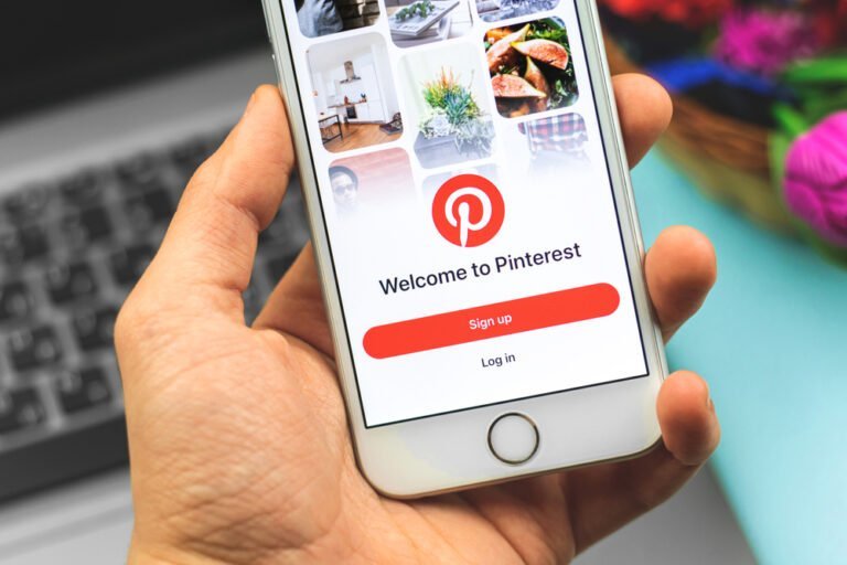 Ruka držící chytrý telefon zobrazující logo mobilní aplikace Pinterest na displeji
