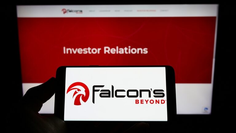 Ruka držící mobilní telefon s logem americké zábavní společnosti Falcon's Beyond