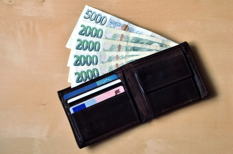 České bankovky a kožená peněže na dřevěném stole