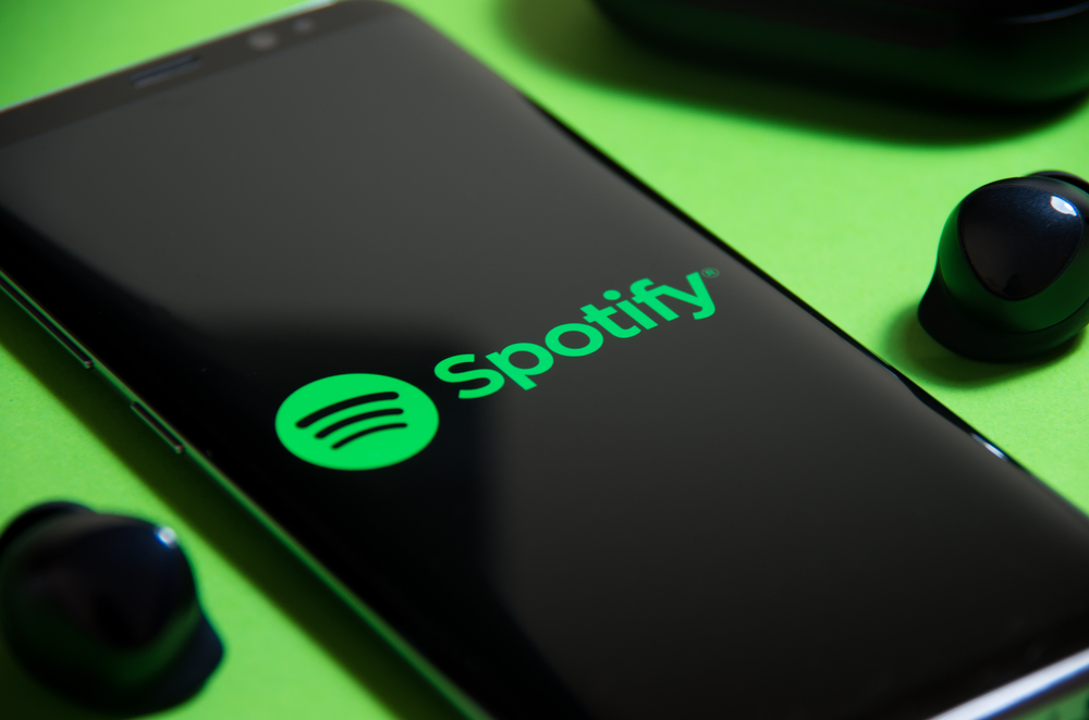 Aplikace Spotify na chytrém telefonu. Streamování hudby a bezdrátová sluchátka, akcie Spotify na vzestupu