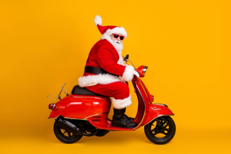 Bělovlasý Santa Klaus sedí na oranžové motorce, žluto oranžové pozadí. Koncept Santa Klaus rally na akciových trzích