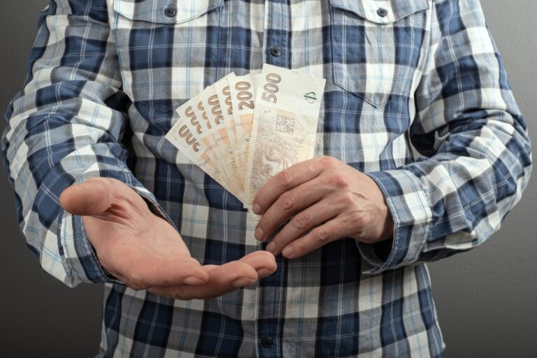 Muž v košili drží v ruce české bankovky, koncept průměrných mezd v ČR