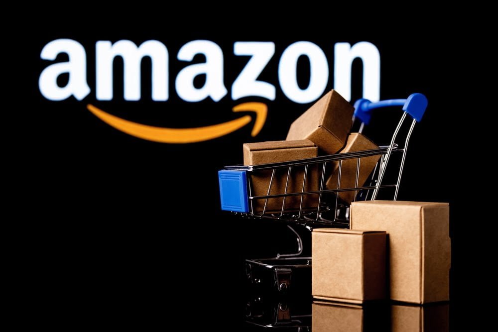 Nákupní košík s krabicemi na černém pozadí s logem Amazon.
