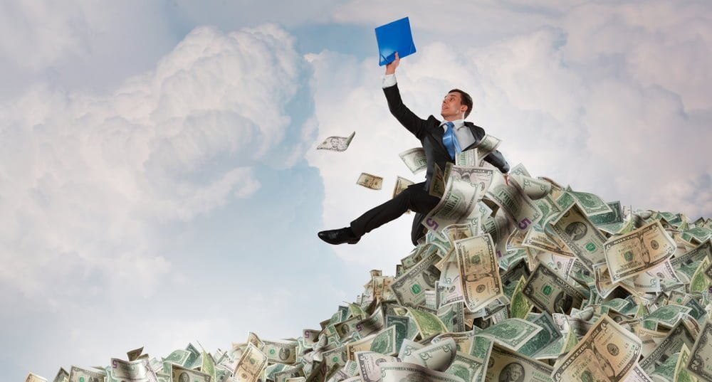 Muž v obleku sedící na kupě peněz, v pozadí oblaky. Koncept indexové fondy a pravidelné investce, které z Vás mohou udělat milionáře. 