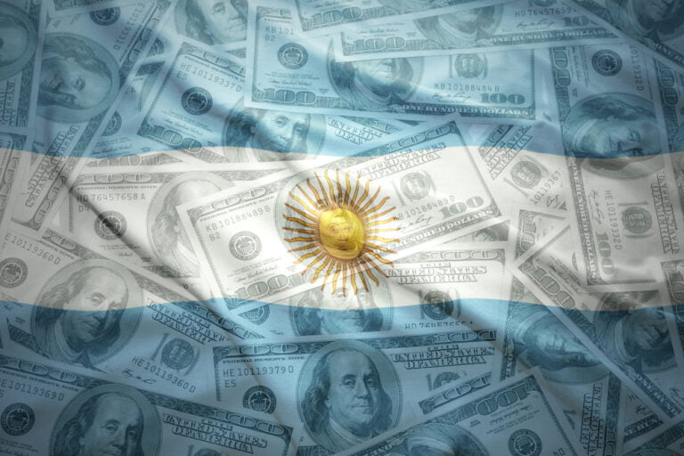 Argentinská vlajka na pozadí a americké dolary. Koncept vysoké inflace v Argentině