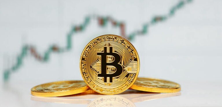 Zlaté mince se symbolem Bitcoinu, v pozadí rostoucí graf