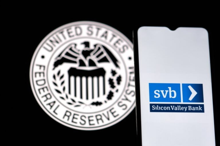 Smartphone s logem SVB (Silicone Valley Bank) a symbol FED