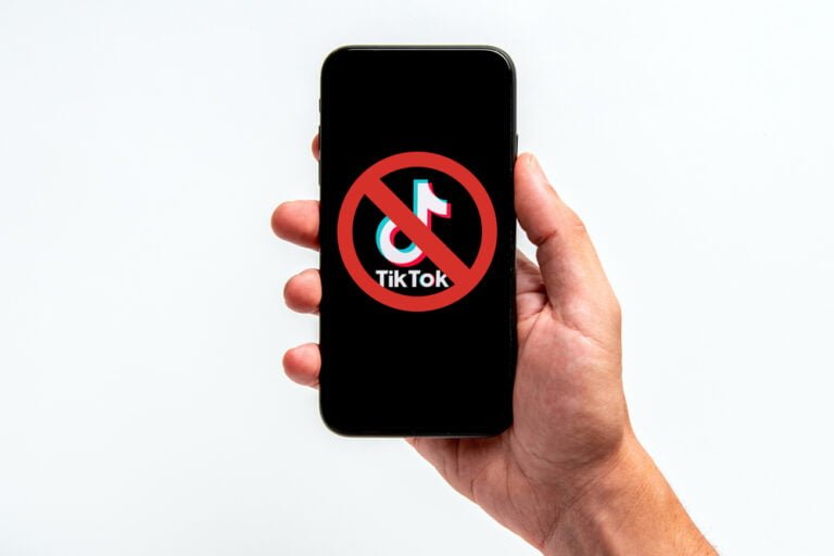 Ruka držící mobilní telefon s aplikací Tik Tok, zákaz používání aplikace