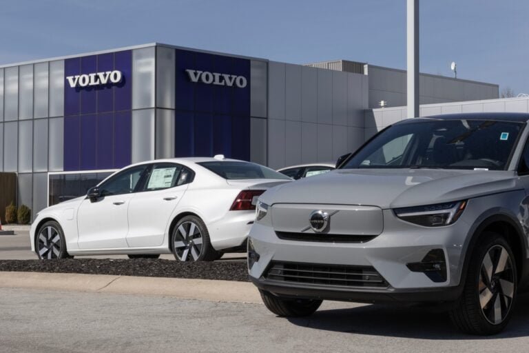 dvě auta značky Volvo stojící na parkovišti před prodejcem aut Volvo